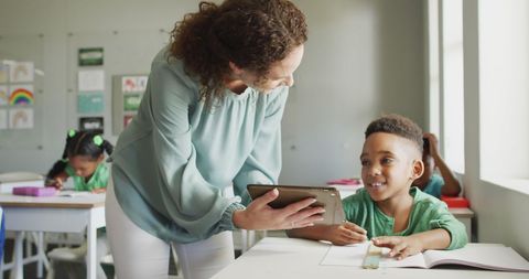 Teacher Helping Schoolboy with Tablet in Classroom