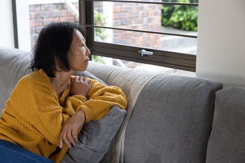 Contemplative senior asian woman relaxing by window