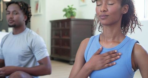African american couple practicing mindful breathing and meditation in sunlit living room
