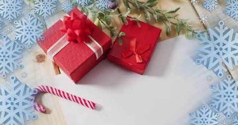 Red christmas gift boxes with candy cane, evergreen sprigs and snowflake border on wood