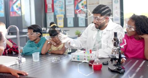 Hands-on chemistry lesson with teacher demonstrating colorful experiment to young students