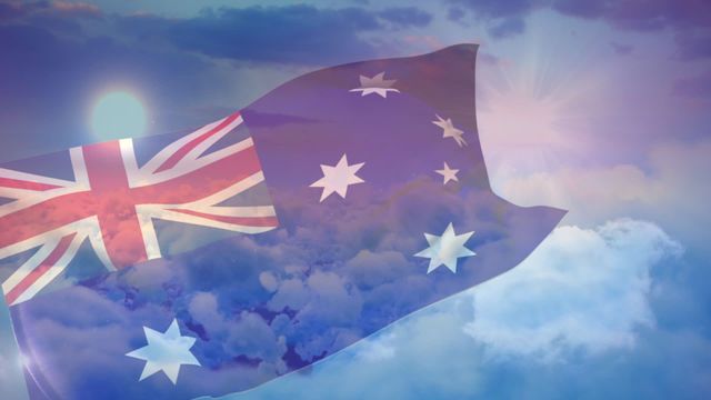 Video depicting the Australian national flag waving against a beautiful cloudy sky with sunlight rays peeking through. Ideal for use in themes related to patriotism, national holidays, travel advertisements, celebratory events, and educational materials about Australia.