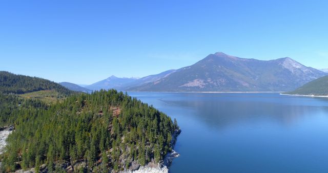 A serene lake nestled between forested hills under a clear blue sky - Download Free Stock Photos Pikwizard.com