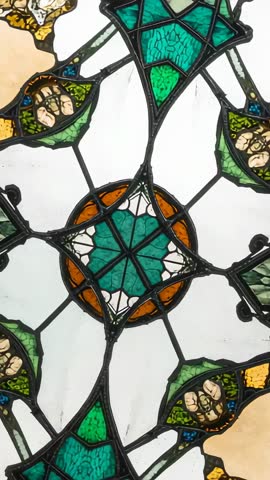 Rotating camera revealing teal rosette in backlit stained glass mosaic vertical video