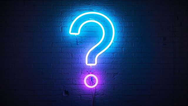 Glowing Neon Question Mark Sign on Brick Wall