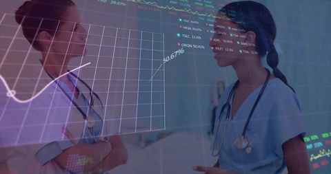 Nurses collaborating over clinical analytics on transparent dashboard in hospital corridor