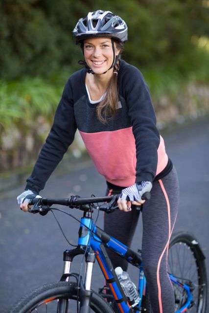 Woman enjoying a cycling adventure on a countryside road, promoting outdoor activities and a healthy lifestyle. Ideal for use in fitness, travel, and outdoor adventure content.