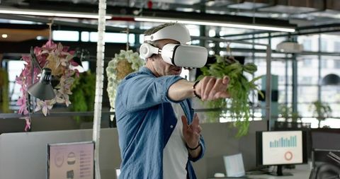 African american man wearing vr headset in green office interacting with virtual analytics