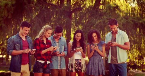 Young Adults Engaging with Smartphones in Park Amidst Nature - Download Free Stock Images Pikwizard.com