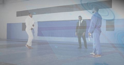 Martial arts instructor guiding whitebelt student during belt test while referee observing