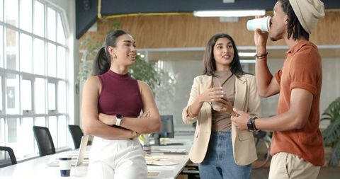 Diverse team collaborating and chatting in modern bright open-plan office