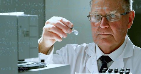 Senior scientist studying glass vial with equations on transparent panel for research