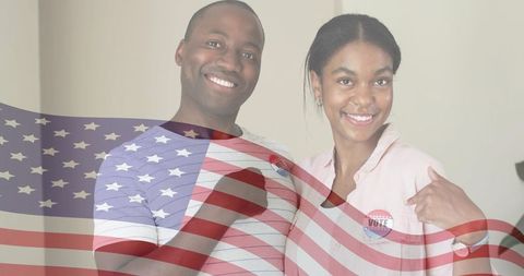 Smiling couple showing i voted stickers with waving american flag overlay