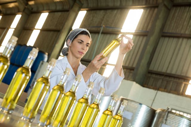 Technician examining olive oil in factory