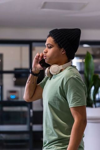 African american man talking on smartphone in modern coworking space with headphones
