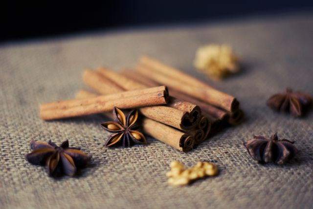 Focus on aromatic cinnamon sticks and star anise on coarse burlap fabric, ideal for autumn and culinary themes. Perfect for promoting baking ingredients, seasonal recipes, or highlighting natural home decor.
