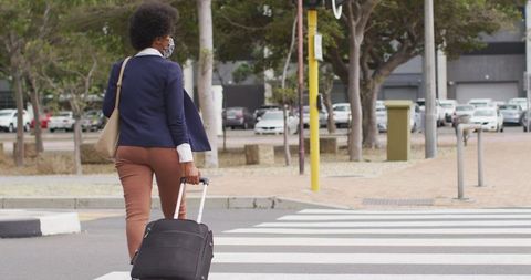 Businesswoman with Luggage and Mask Walking Across Crosswalk