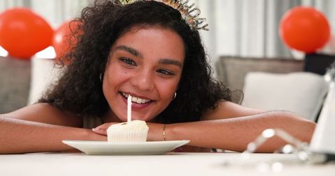 Young Woman Celebrating Birthday with Cupcake and Candle