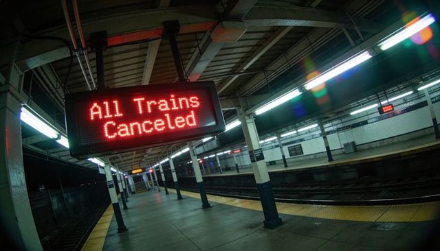 Displaying red LED All Trains Canceled sign on empty subway platform with fluorescent lighting