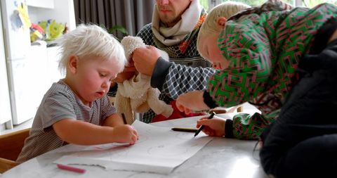 Father Dressing Daughter While Son Colors at Table