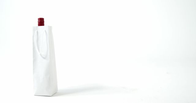 Wine bottle peeking out of white gift bag on seamless white background. Elegant and understated, perfect for themes of gifting, celebrations, or minimalist presentations. Great for advertising gift shops, wine stores, or special occasions.