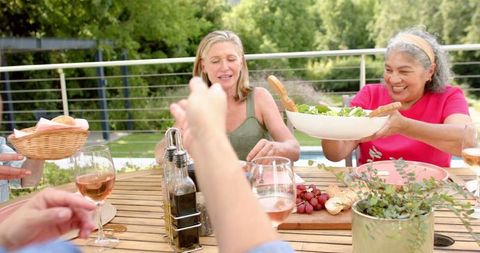 Diverse senior friends sharing outdoor meal around table