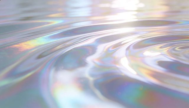 Iridescent liquid surface rippling with pastel holographic refractions and soft bokeh