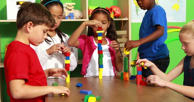 Diverse group of young children engaged in group activity, building with colorful blocks in classroom. Children are practicing teamwork, creativity, and problem-solving skills. Perfect for materials related to early education, child development, learning activities, and promoting diversity in educational settings.