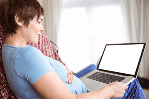 Pregnant Woman Relaxing with Transparent Laptop Screen at Home