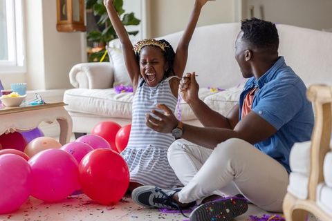 African american father and daughter celebrating birthday with balloons in living room