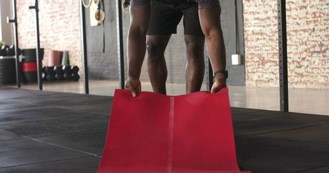 Man Unrolling Exercise Mat in Industrial Style Gym