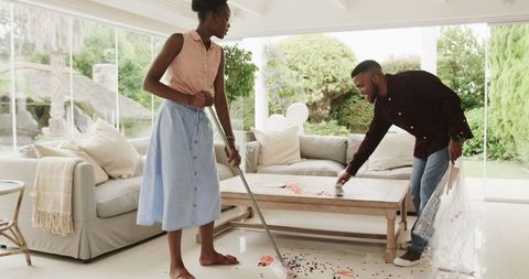 Young Couple Tidying Living Room After Celebration