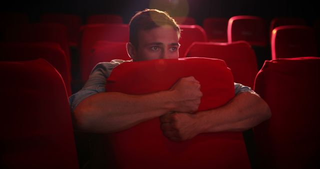 Man in cinema seats holding cushion with focus - Download Free Stock Images Pikwizard.com