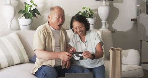 Senior couple celebrating pregnancy announcement via video call