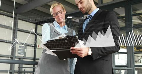 Business professionals reviewing analytics on clipboard showing digital charts and graphs