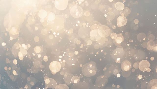 Glowing bokeh light orbs drifting across soft neutral backdrop, golden dust particles sparkle