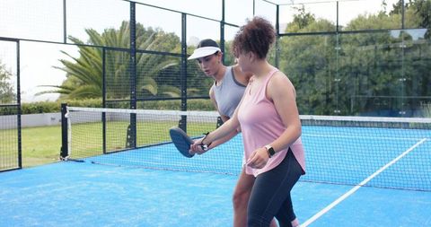 African american women practicing padel on blue court coaching and training outdoors