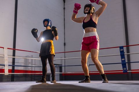 Female boxers sparring in ring showing victory moment and athletic intensity