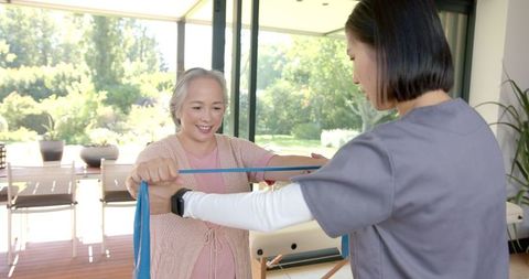 Senior Woman Exercising with Therapist at Home for Rehabilitation