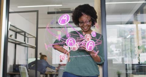 Woman interacting with holographic social network on glass wall in modern office space