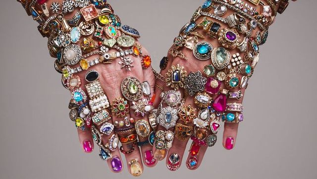Hands wearing stacked gemstone rings and layered bracelets with colorful nail art