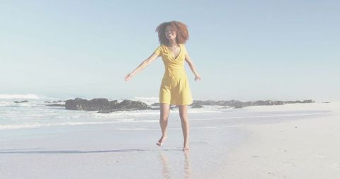 Joyful woman in yellow dress on serene beachfront