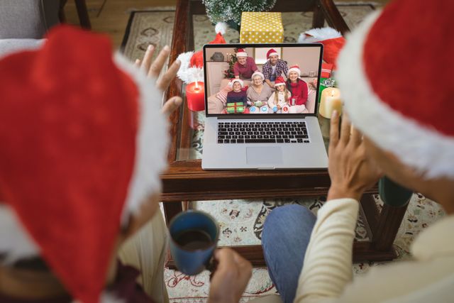 Diverse couple with santa hats having video call with happy caucasian family. Christmas, celebration and digital composite image.