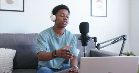 Male podcaster recording from home studio with headset and laptop