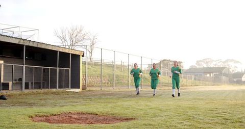 Diverse Female Athletes Jogging on Softball Field at Sunrise