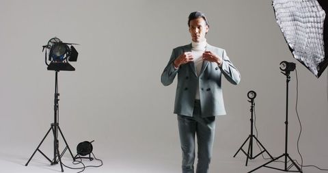 Fashionable man adjusting suit in professional photography studio