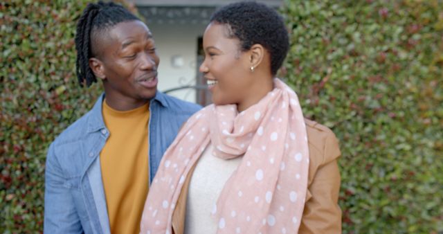 Happy african american couple embracing outside a house. Outdoors, togetherness, love and casual lifestyle concept, unaltered.