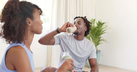 African american couple relaxing on floor drinking morning beverages in sunlit living room