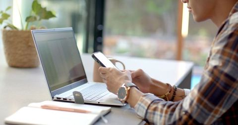 Business Professional Checking Smartphone with Laptop