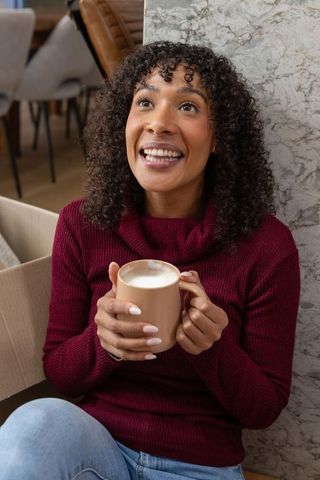 Joyful Woman Enjoying Warm Drink in Chic Cafe Interior